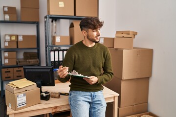 Young arab man ecommerce business worker writing on checklist at office