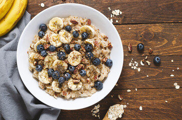 Oatmeal Bowl, Oat Porridge with Blueberry, Banana and Pecans in a Bowl on Wooden Background, Healthy Snack or Breakfast