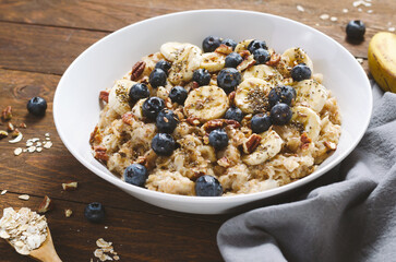 Oatmeal Bowl, Oat Porridge with Blueberry, Banana and Pecans in a Bowl on Wooden Background, Healthy Snack or Breakfast
