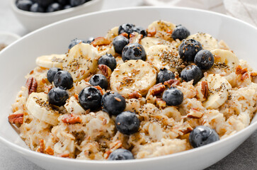 Oatmeal Bowl, Oat Porridge with Blueberry, Banana and Pecans in a Bowl on Bright Background, Healthy Snack or Breakfast