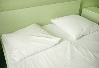 Light green tinting, close-up of white sheets and pillow in a hotel room, modern interior