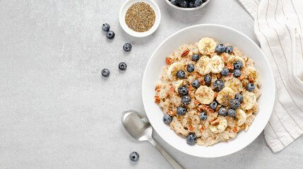 Fototapeta na wymiar Oatmeal Bowl, Oat Porridge with Blueberry, Banana and Pecans in a Bowl on Bright Background, Healthy Snack or Breakfast