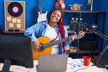 Fototapeta na wymiar African american woman musician singing song playing classical guitar at music studio