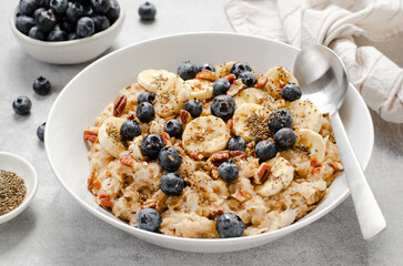 Oatmeal Bowl, Oat Porridge with Blueberry, Banana and Pecans in a Bowl on Bright Background, Healthy Snack or Breakfast