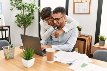 Two hispanic men couple hugging each other working at office