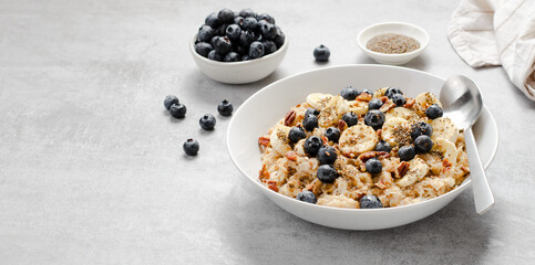Oatmeal Bowl, Oat Porridge with Blueberry, Banana and Pecans in a Bowl on Bright Background, Healthy Snack or Breakfast
