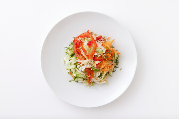 Plate of summer vegetable salad with cucumbers, tomatoes, cabbage and carrot isolated at white background.