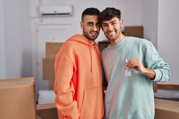 Two man couple hugging each other holding key at new home