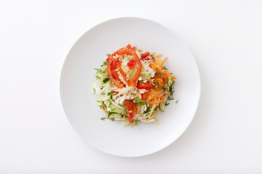 Plate of summer vegetable salad with cucumbers, tomatoes, cabbage and carrot isolated at white background.