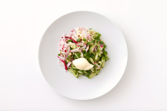 Plate of vegetable salad with cucumbers, radish, and eggs isolated at white background.