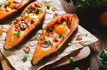 Baked Sweet Potato Stuffed with Egg, Bacon, and Green Onions on Wooden Rustic Background