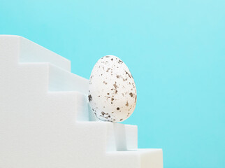 Modern composition made of Easter egg on white stairs. Pastel blue background. Background for branding and packaging presentation. Product concept.