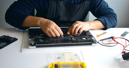 Computer technician, laptop motherboard repairer is dismantling the parts of a notebook computer...