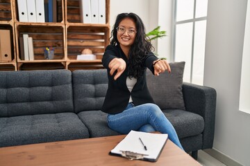 Obraz premium Young asian woman at consultation office pointing to you and the camera with fingers, smiling positive and cheerful