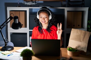 Young asian woman working at the office with laptop at night showing and pointing up with fingers number three while smiling confident and happy.