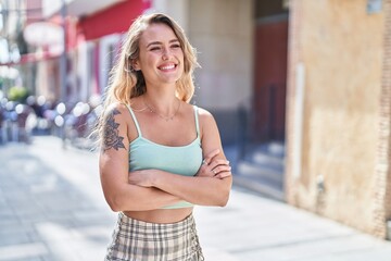 Young blonde woman standing with arms crossed gesture at street