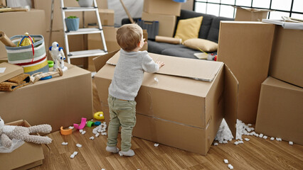 Caucasian toddler playing with cardboard box at new home