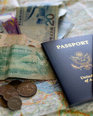 two US American passports laying on large road map of foreign country close-up with foreign currency bills and coins