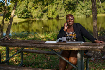 Fototapeta premium Happy businesswoman working from a table in a park