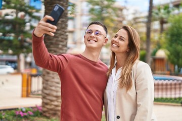 Man and woman mother and son smiling confident make selfie by the smartphone at park