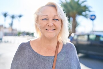 Middle age blonde woman smiling confident standing at street