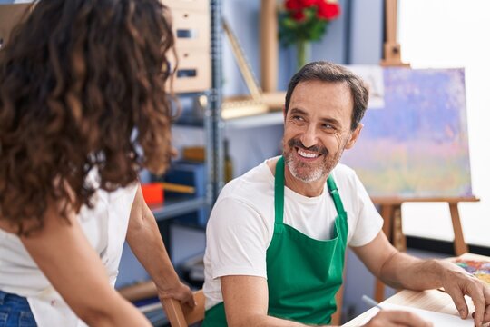 Man and woman artists smiling confident drawing on notebook at art studio