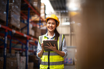 Asian female worker wearing Hard Hat Checks Stock and Inventory with clipboard in the Retail Warehouse.