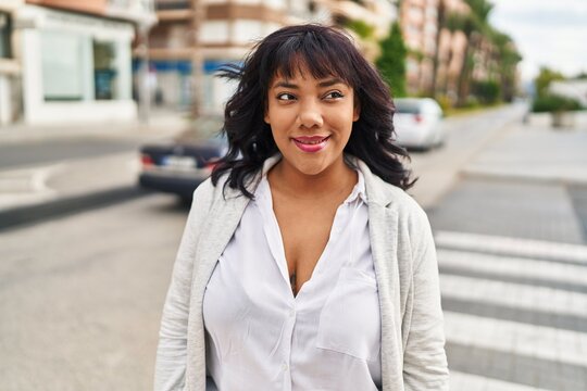 Young beautiful latin woman smiling confident looking to the side at street