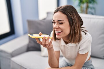 Young beautiful hispanic woman talking on the smartphone sitting on sofa at home