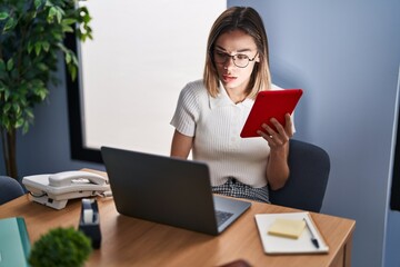 Young beautiful hispanic woman business worker using touchpad and laptop at office
