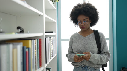 Fototapeta na wymiar African american woman student using smartphone at library university