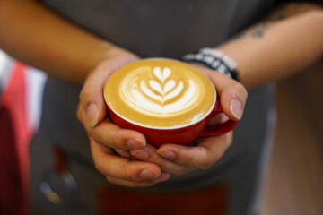 close up of a person holding a cup of coffee. Rosetta latte art coffee