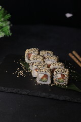 Sushi rolls on black background with salmon cheese and fish