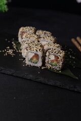Sushi rolls on black background with salmon cheese and fish