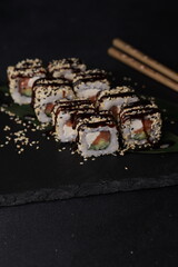 Sushi rolls on black background with salmon cheese and fish