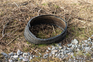 Delaminated truck tire in a ditch by a road.
