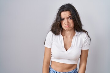 Young teenager girl standing over white background depressed and worry for distress, crying angry and afraid. sad expression.