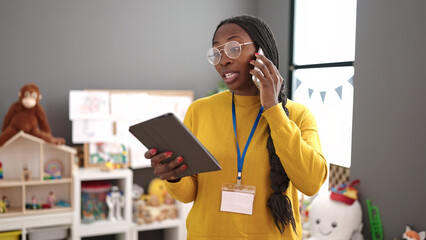 African woman working as teacher with tablet speaking on the phone at kindergarten