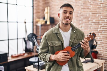 Young hispanic man musician playing ukelele at music studio