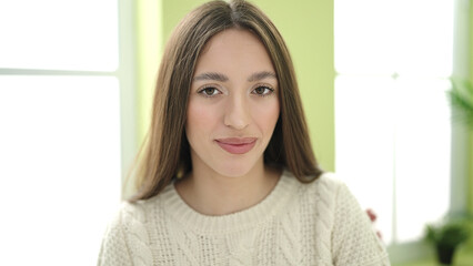 Young beautiful hispanic woman smiling confident sitting on table at home