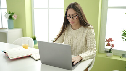 Young beautiful hispanic woman student using laptop studying at home