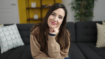 Fototapeta premium Beautiful hispanic woman smiling confident sitting on sofa at home