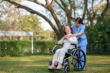 Fototapeta premium Asian nurse or physiotherapist caring for elderly woman sitting wheelchair
