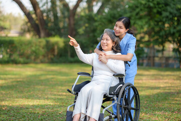 Asian nurse or physiotherapist caring for elderly woman sitting wheelchair