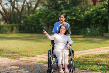 Asian nurse or physiotherapist caring for elderly woman sitting wheelchair