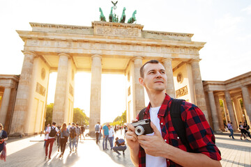 Travel in Berlin, tourist man with camera in front of Brandenburg Gate, Berlin, Germany