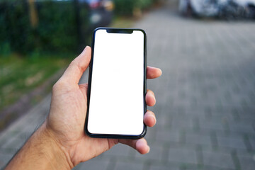 Man holding smartphone showing white blank screen at street