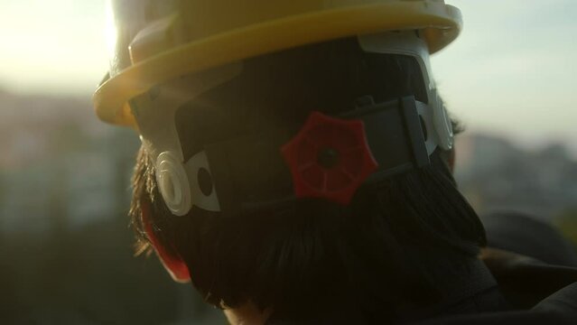 Young construction engineer or contractor in suit takes off his helmet in extreme close-up, sunny weather