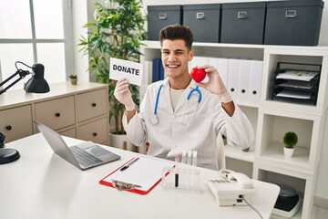 Young hispanic doctor man supporting organs donations winking looking at the camera with sexy expression, cheerful and happy face.