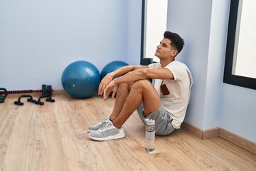 Young hispanic man tired relaxed sitting on floor at sport center